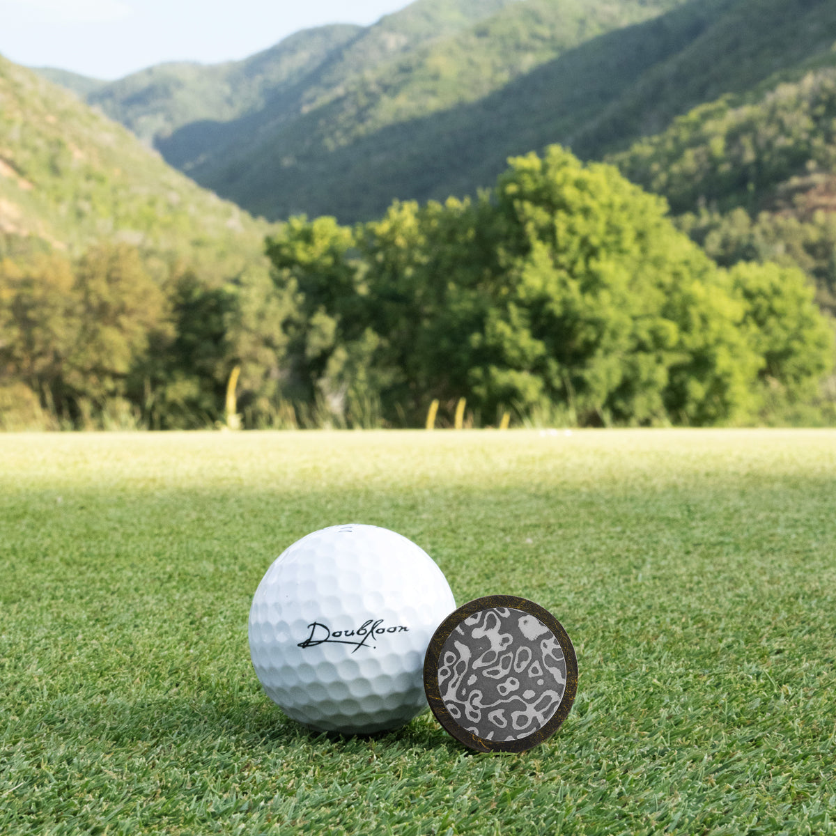 The Calico Jack Golf Ball Marker — alternate angle showing carbon fiber and Damascus steel finish