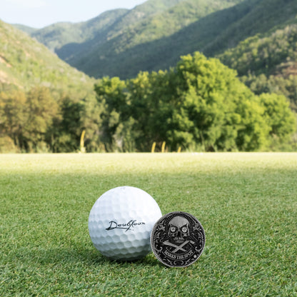 Golf ball and custom luxury golf ball marker with diamonds set in sterling silver and skull design on grass with mountains in the background
